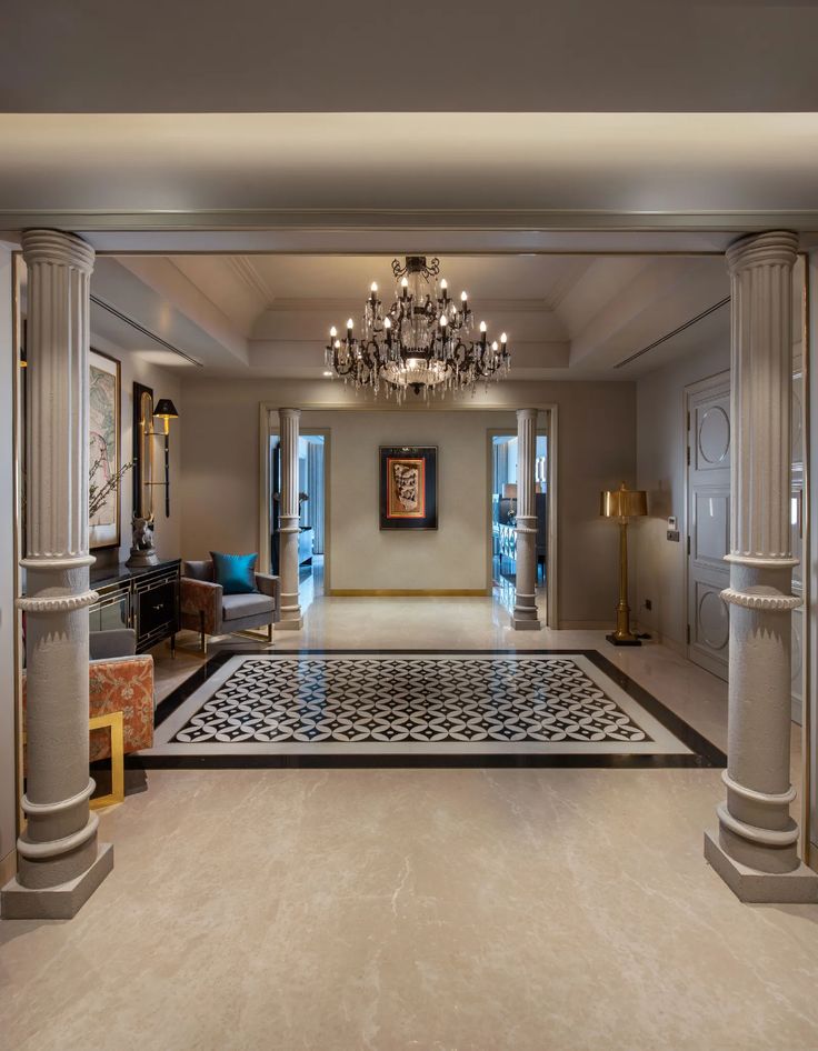 an elegant entry way with chandelier and marble flooring in the foyer area