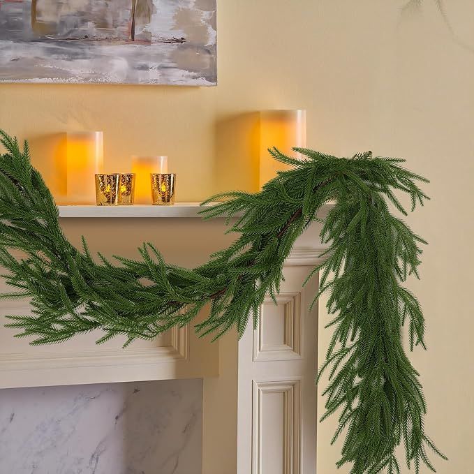 candles are lit on the mantle in front of a decorated christmas tree branch with pine needles