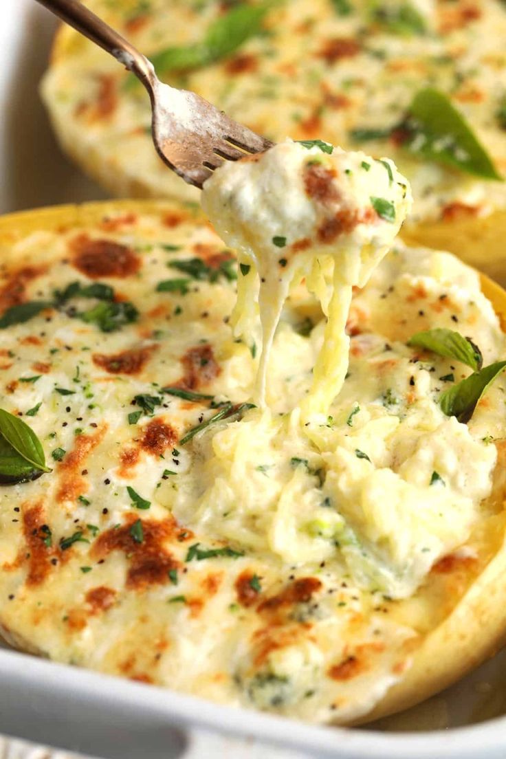 a spoon is lifting some food out of a casserole dish with cheese and spinach