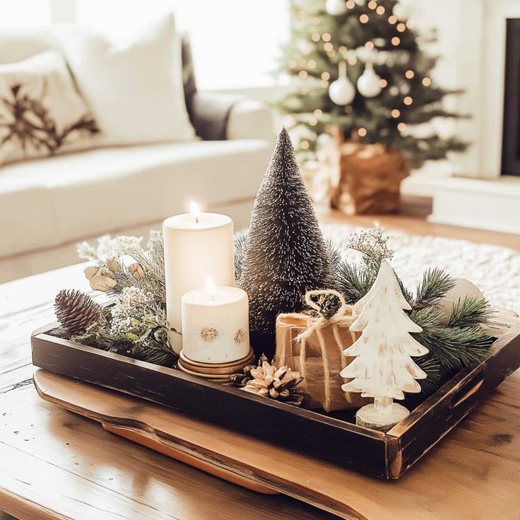 a tray filled with christmas decorations and candles on top of a wooden table next to a couch