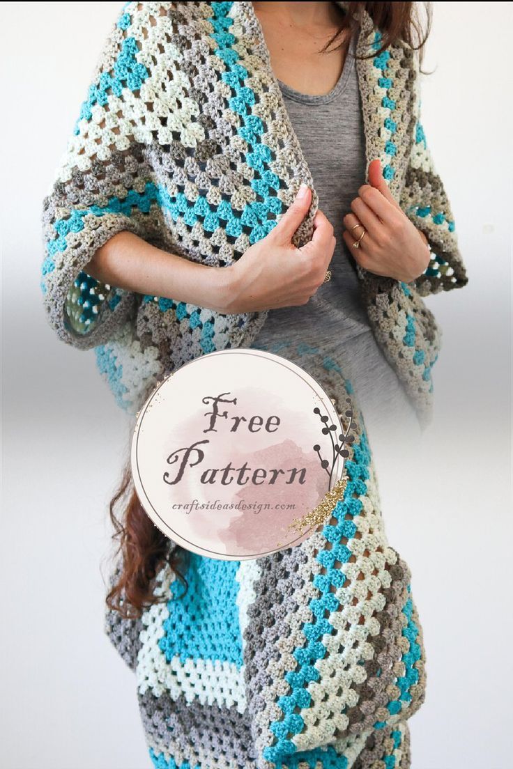 a woman wearing a blue and gray crocheted shawl holding a free pattern