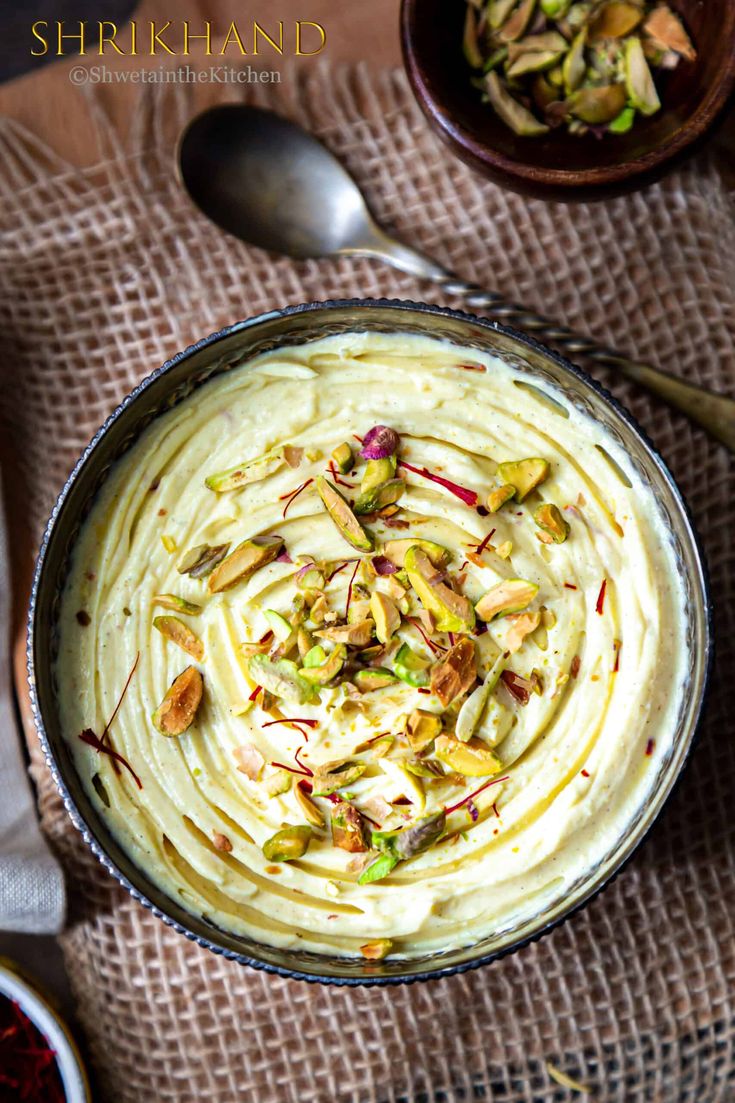 a bowl filled with hummus and nuts on top of a cloth next to two spoons