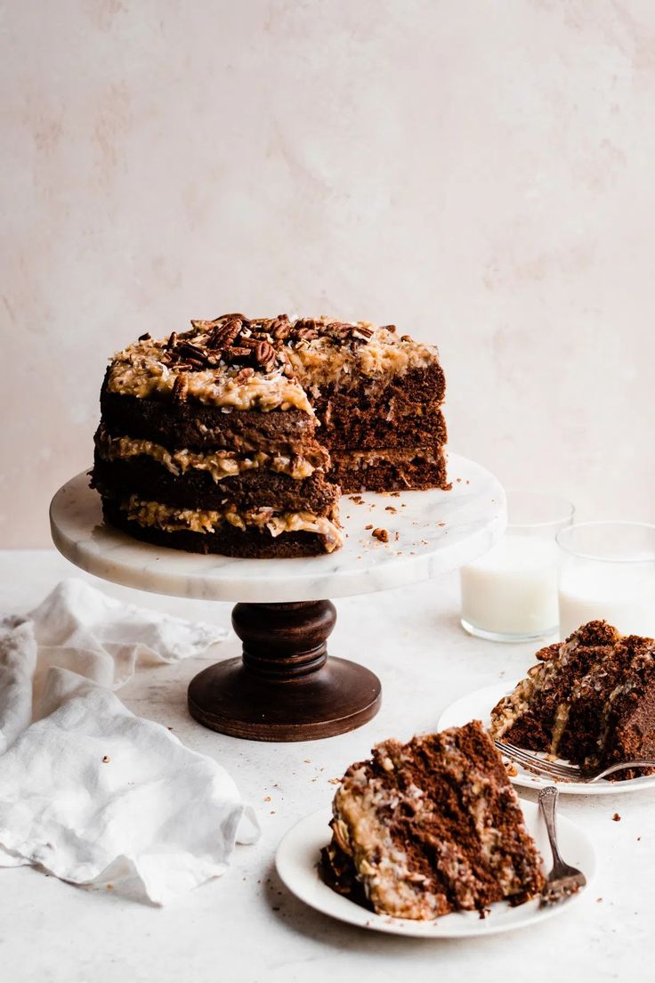 a chocolate cake on a plate with one slice cut out and two glasses of milk next to it