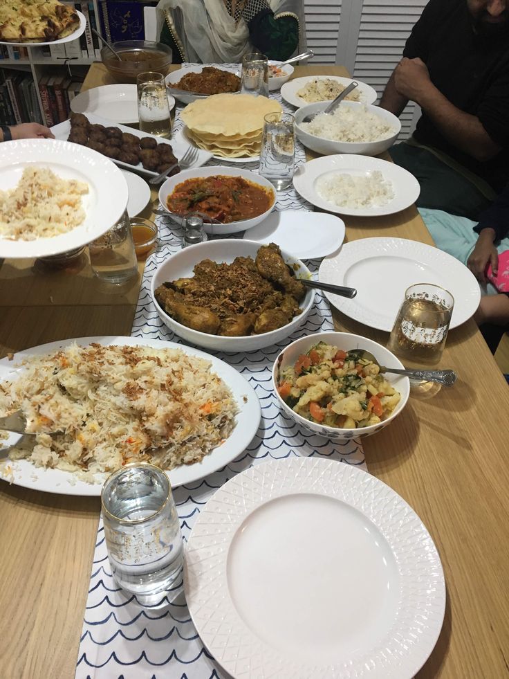 a table full of food and people sitting at the table with plates, bowls and glasses