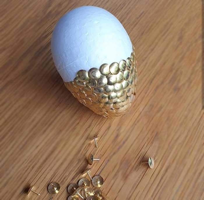 a wooden table topped with lots of gold and white buttons next to a ball on top of wood