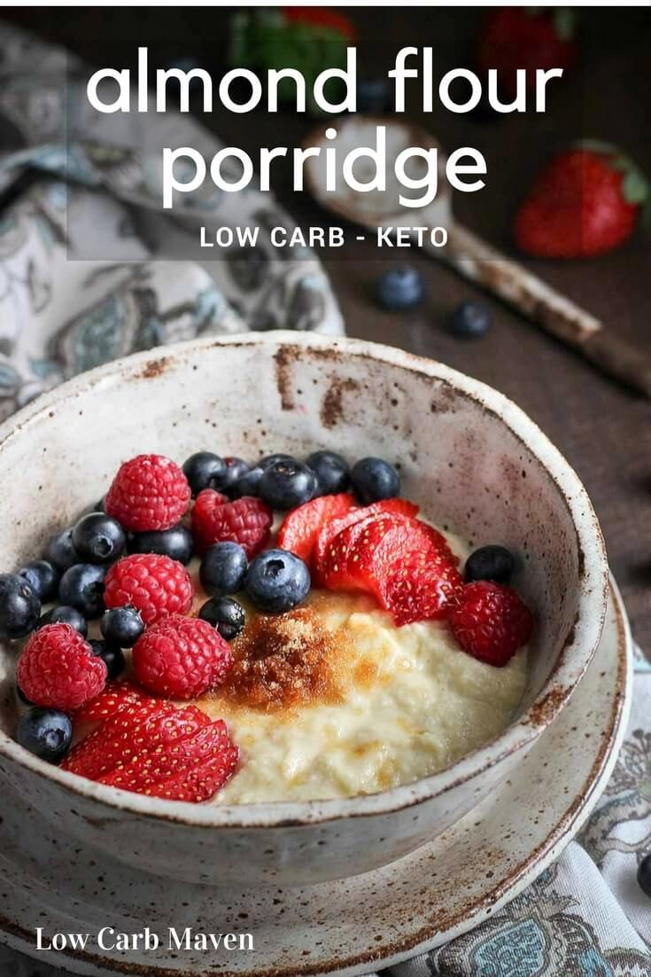 a bowl filled with berries and blueberries on top of a wooden table next to spoons