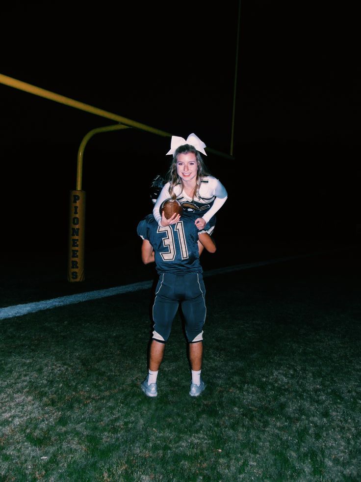 a woman holding a child in her arms while standing on top of a football field