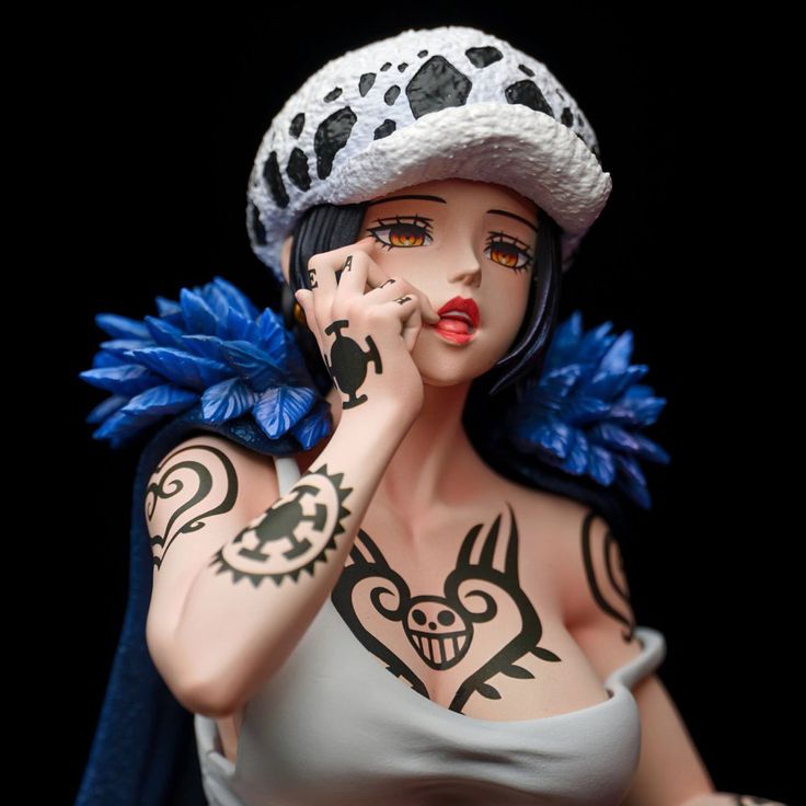 a woman with black and white tattoos holding her hand to her face while wearing a hat