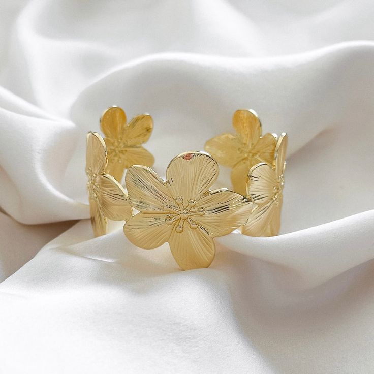 Make a statement with our chunky floral cuff bracelet thats easy to wear and style. Wear alone or layer with other bracelets. 14k Gold Filled Cuff Diameter: 52mm x 34mm Adjustable Hypoallergenic Water resistant & tarnish free Nickel & lead free Gold Bracelet Jewelry For Spring, Spring Gold Bracelet Jewelry, Gold Spring Bracelet, Elegant Spring Bracelets In Flower Shape, Elegant Flower-shaped Bracelets For Spring, Elegant Spring Flower-shaped Bracelets, Gold Bangle Bracelets For Spring, Spring Bangle Jewelry Gift, Gold Bangle Bracelet For Spring