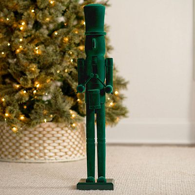 a green toy standing next to a christmas tree