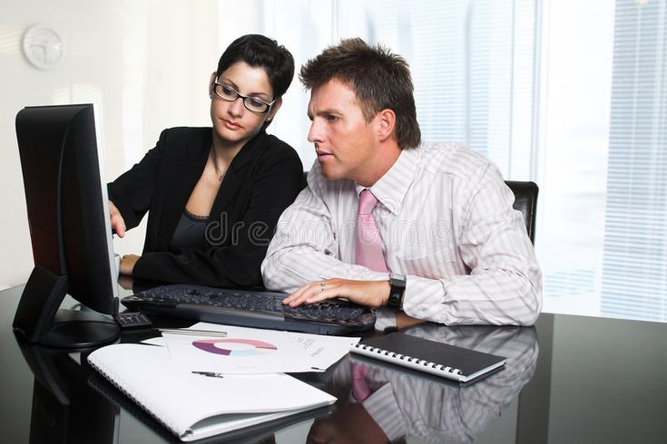 a man and woman sitting at a desk looking at a computer screen