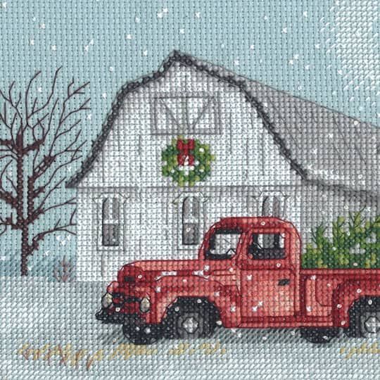 a red truck is parked in front of a white barn with wreaths on it