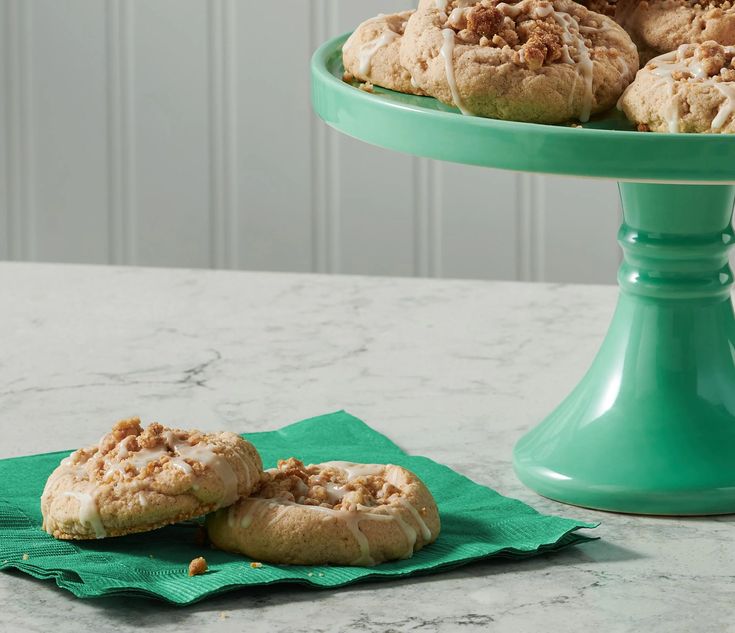 several pastries are on a green plate next to a cake stand with two plates