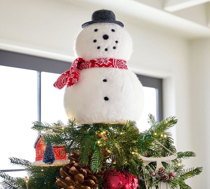 a snowman sitting on top of a christmas tree