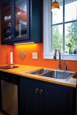 an orange kitchen with black cabinets and stainless steel sink, dishwasher and window