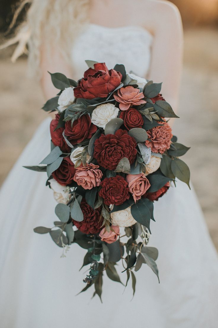 a bridal holding a bouquet of red and white flowers