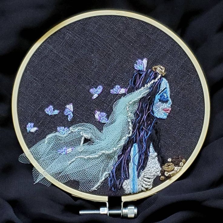 a woman with blue hair and butterflies in her hand is depicted on a black background