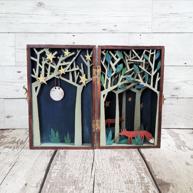 two wooden boxes with cut out animals in the trees and stars hanging from each box