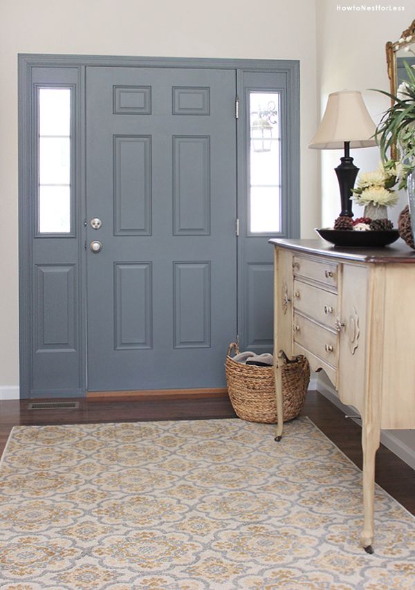 a blue door in a white room with a rug on the floor next to it