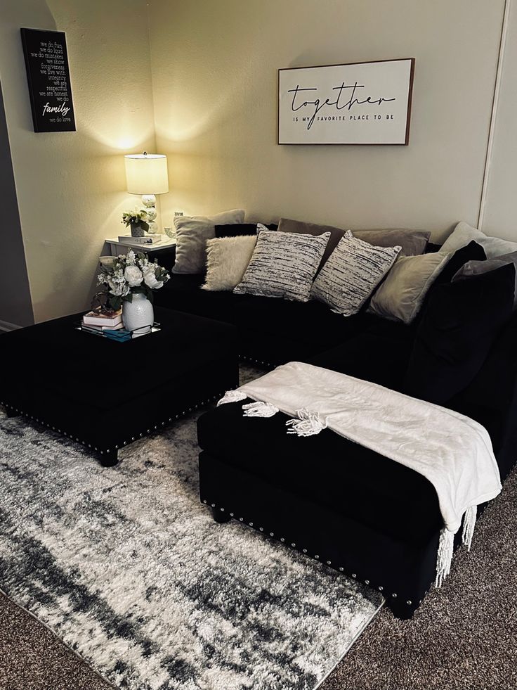 a living room with a large black couch and white rug on the floor next to a lamp