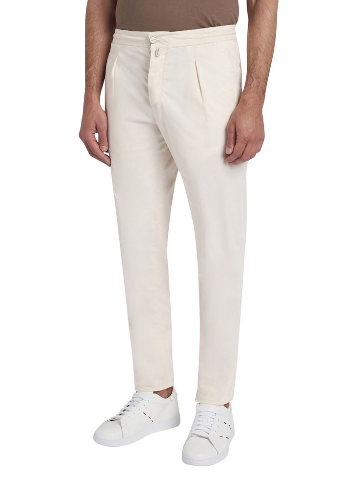 Ivory-coloured cotton trousers with jogger-style waist. The Kiton trouser, an icon of casual style, is reinterpreted with a relaxed twist thanks to volumes that are roomier at the pelvis, wide on the leg and narrower at the bottom in order to offer an authentic experience of comfort. The drawstring waist with a sporty soul meets darts inspired by the world of tailoring to express the casual and elegant vocation of the garment. The opening of the leg is 18 cm on a base size of 50 (Italian). We recommend hand washing inside-out at 30 C. Dry cleanComposition: 97% Cotton, 3% Elastane, Detail, 100% Cotton Cream Relaxed Fit Pants With Straight Hem, White Chinos With Straight Hem For Spring, Modern Relaxed Fit Cotton Chinos, Neutral Cotton Pants With Straight Hem, White Cotton Chinos With Welt Pockets, Off White Cotton Straight Pants, High-waisted Beige Cotton Chinos, Beige High-waisted Cotton Chinos, Classic Cream Tapered Leg Pants