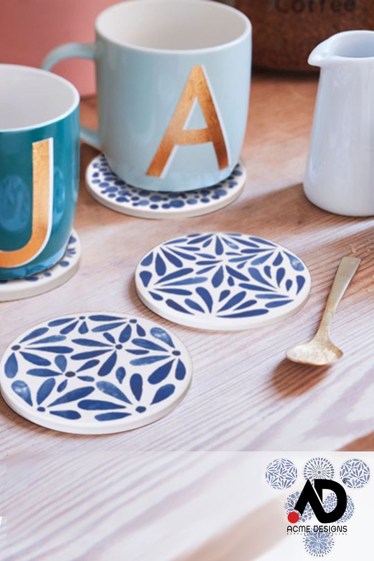 three blue and white plates sitting on top of a wooden table next to two mugs