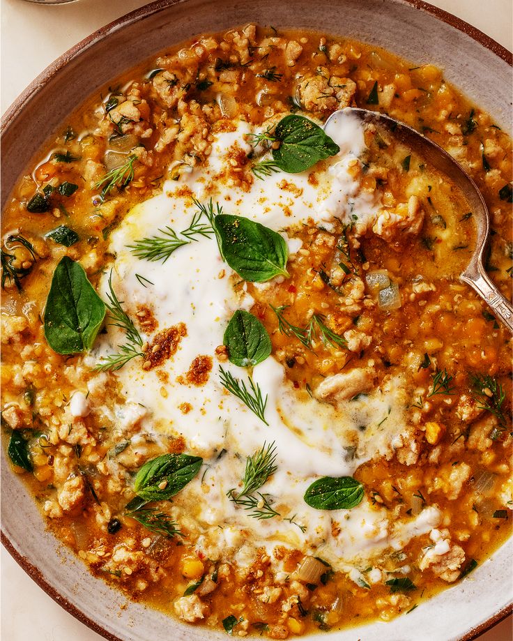 a bowl of soup with spinach, cheese and herbs on the side is ready to be eaten