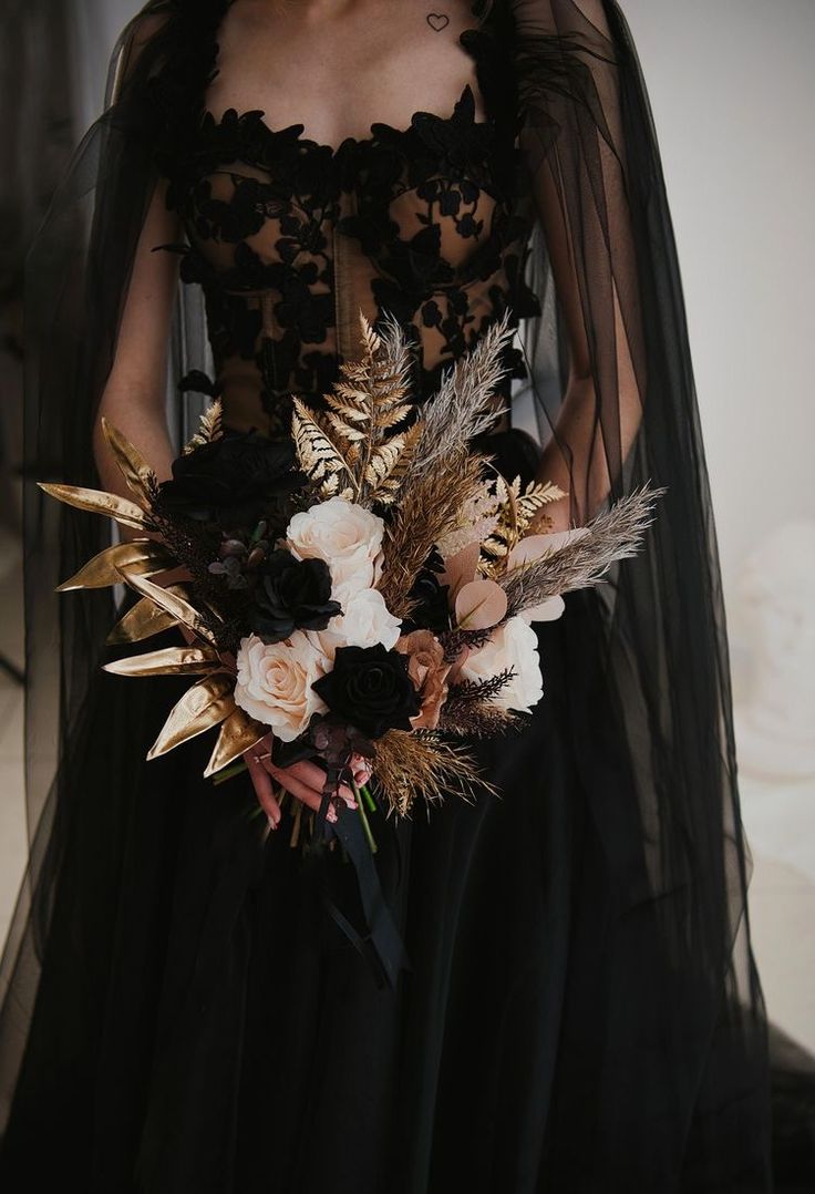 a woman in a black dress holding a bouquet with feathers on it's back