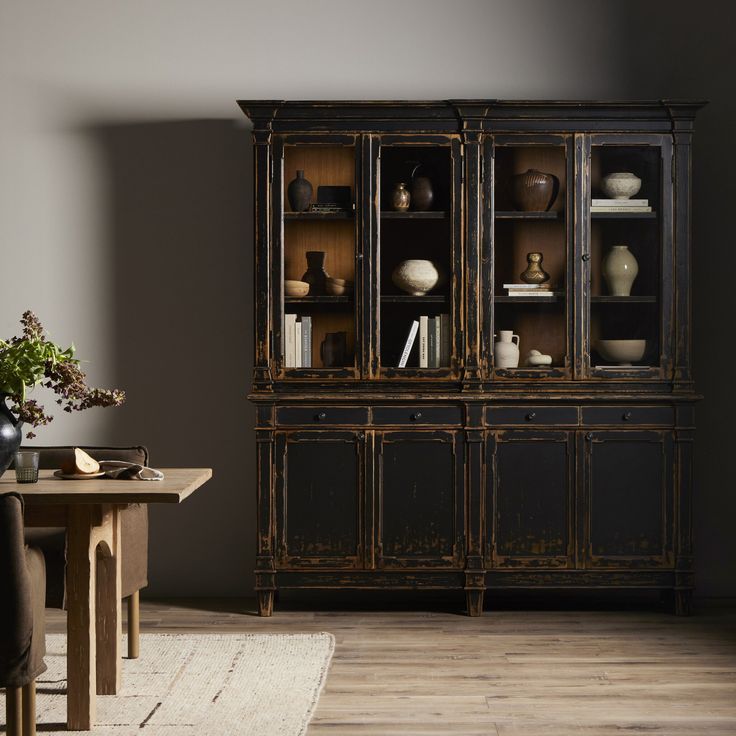 a room with a table, chair and china cabinet in it's centerpiece