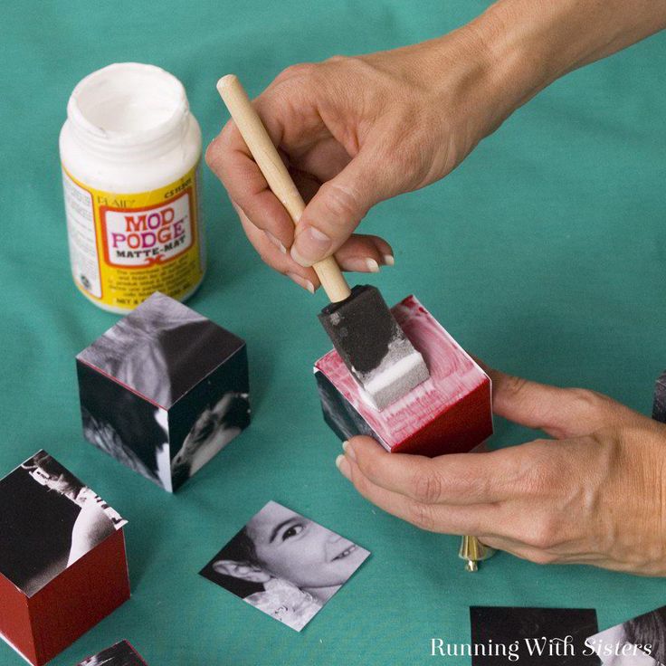 a person holding a match box with matches in it and some pictures on the table