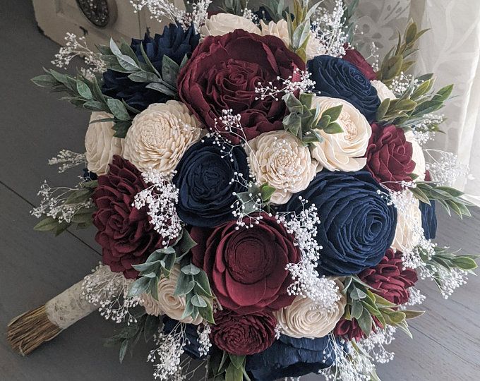 a bridal bouquet with red, white and blue flowers on the floor in front of a door