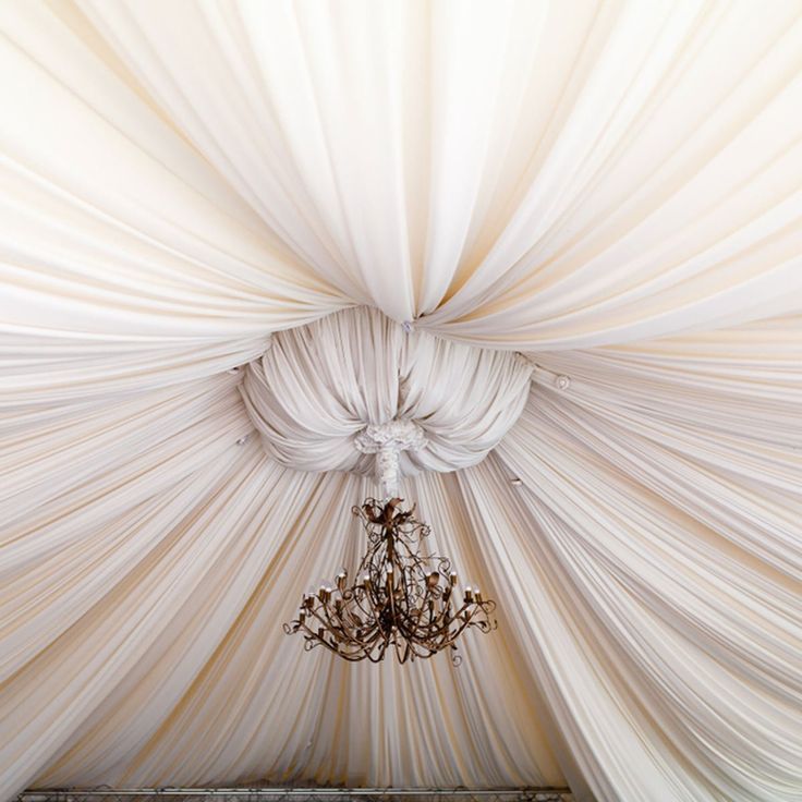 a chandelier hanging from the ceiling in a room with drapes on it