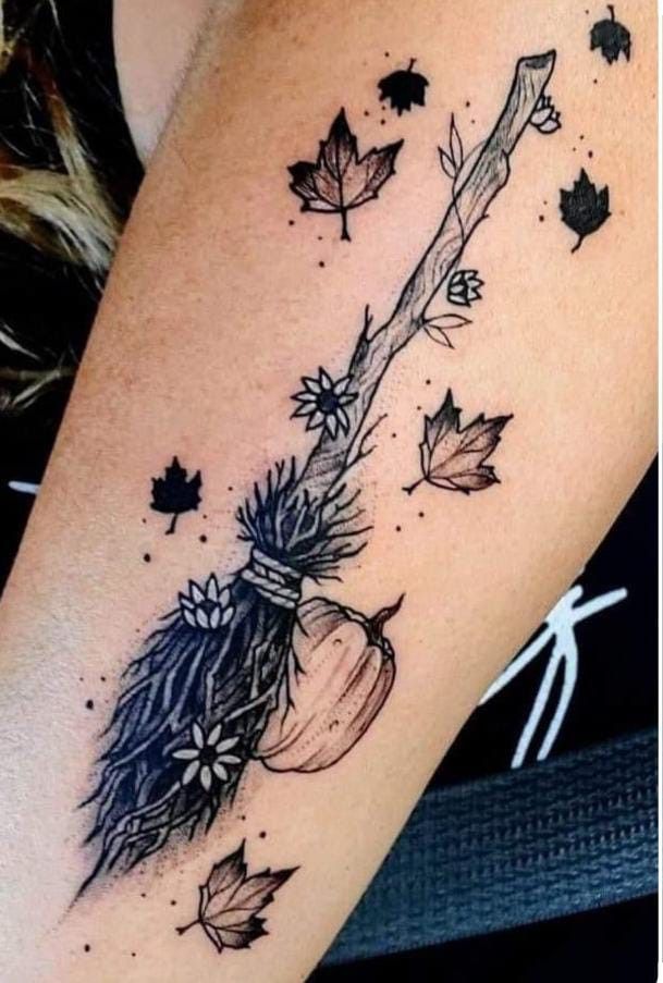 a woman's arm with an arrow and leaves on it