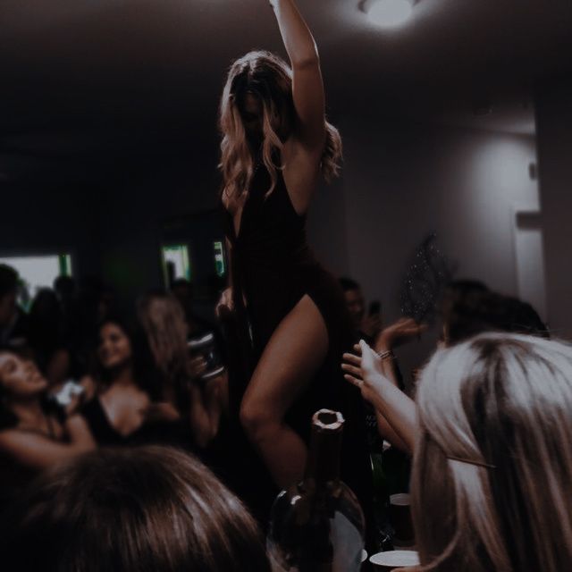 a woman standing on top of a wine bottle in front of a group of people