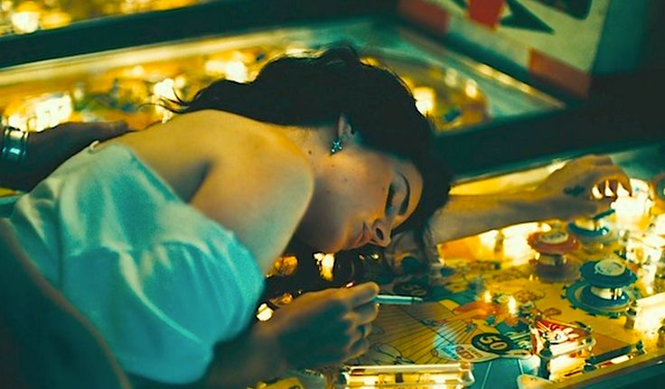 a woman standing in front of a pinball machine