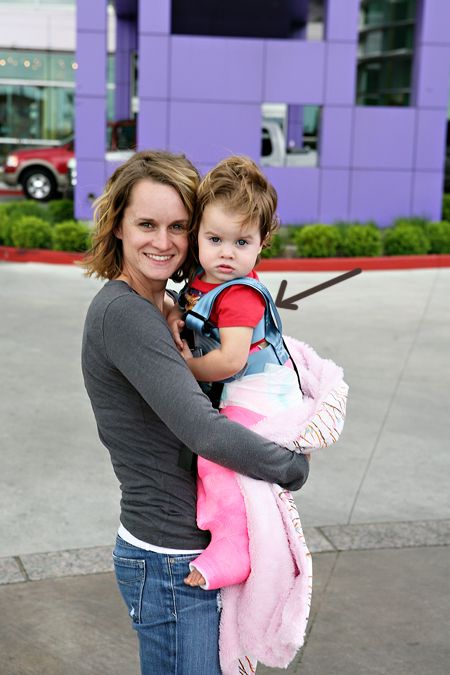 a woman holding a child in her arms on the sidewalk near a building with purple walls