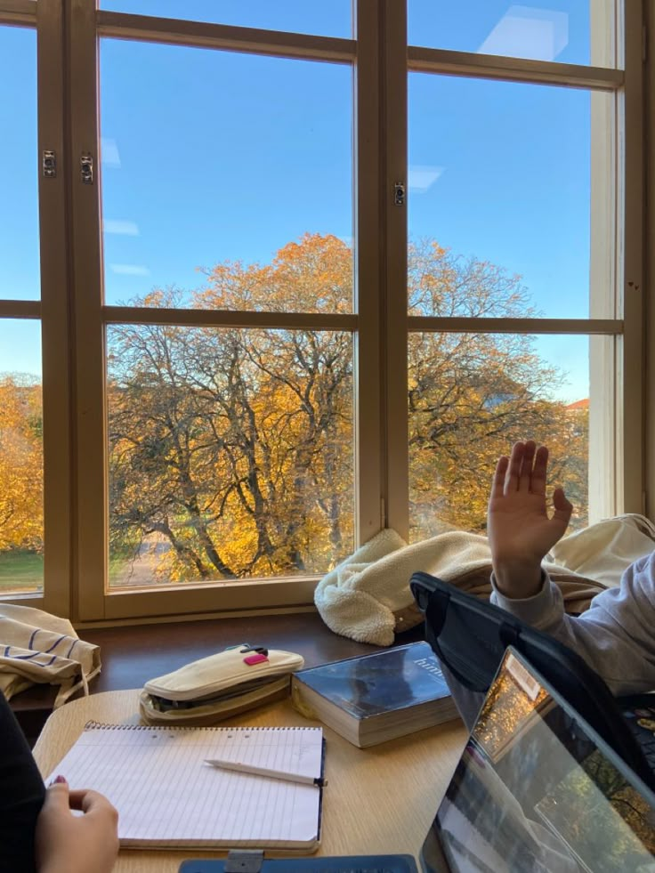 a person sitting in front of a window with their hand up and looking out the window