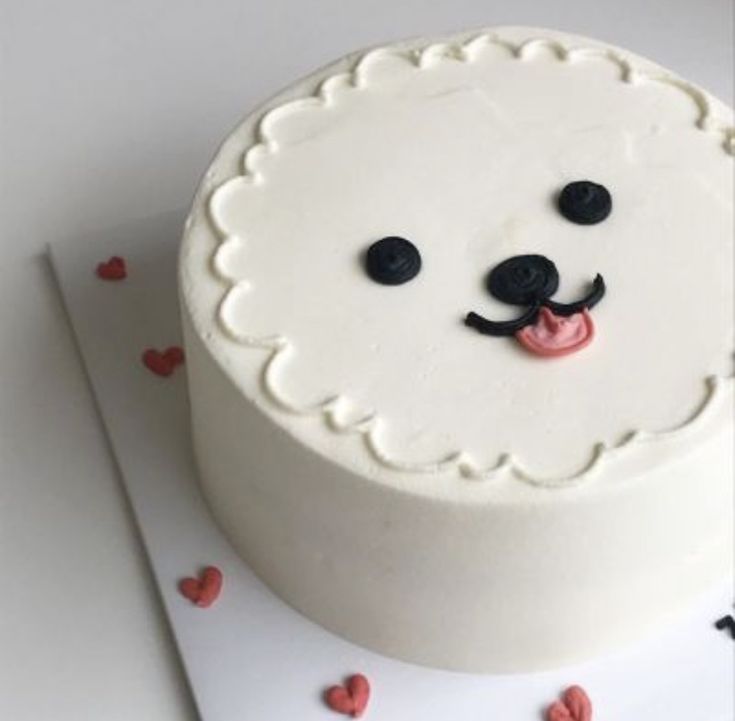 there is a cake with a bear face on the top and red hearts around it