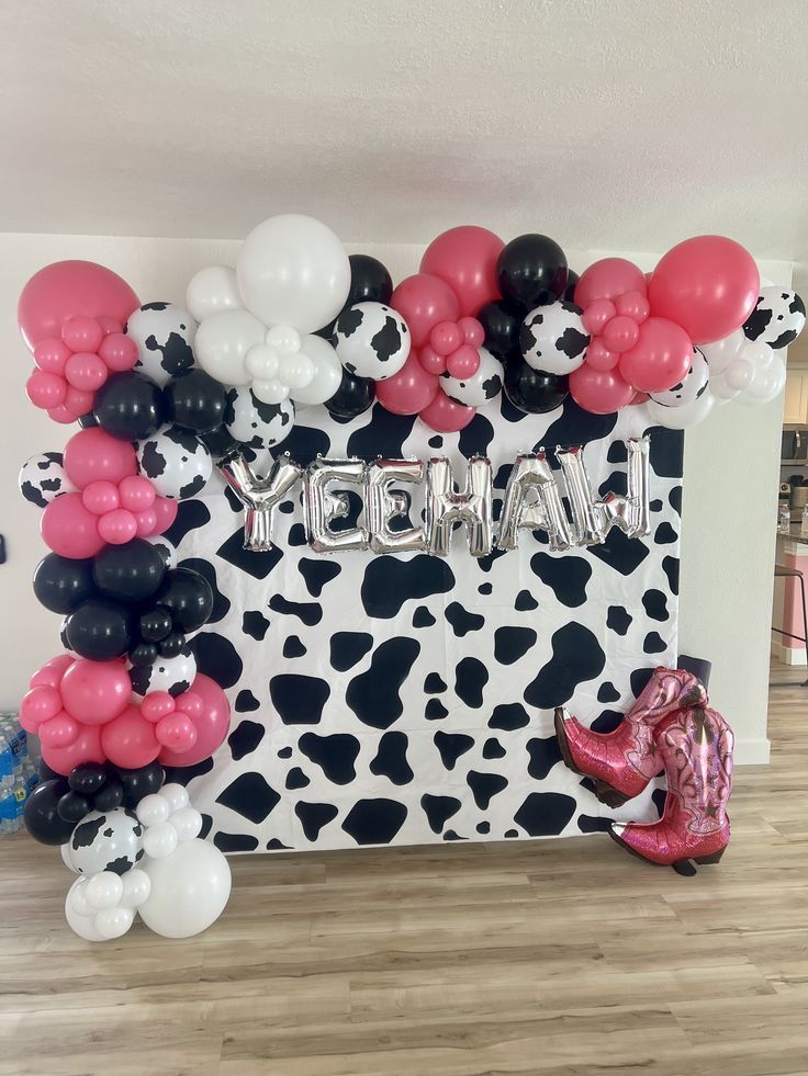 the balloon arch is decorated with black, white and pink balloons that spell out happy