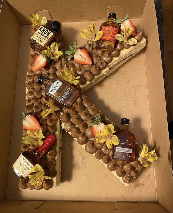 a cake shaped like the letter k with nuts and fruit on it in a box