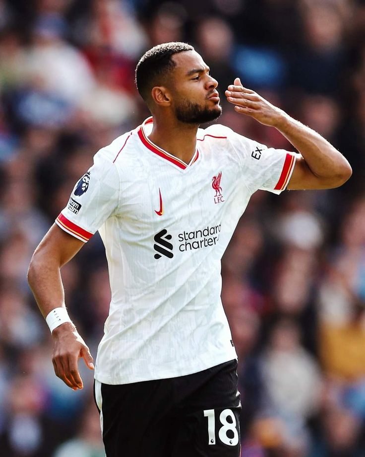 a soccer player with his hand up to his face while looking at the ball in front of him