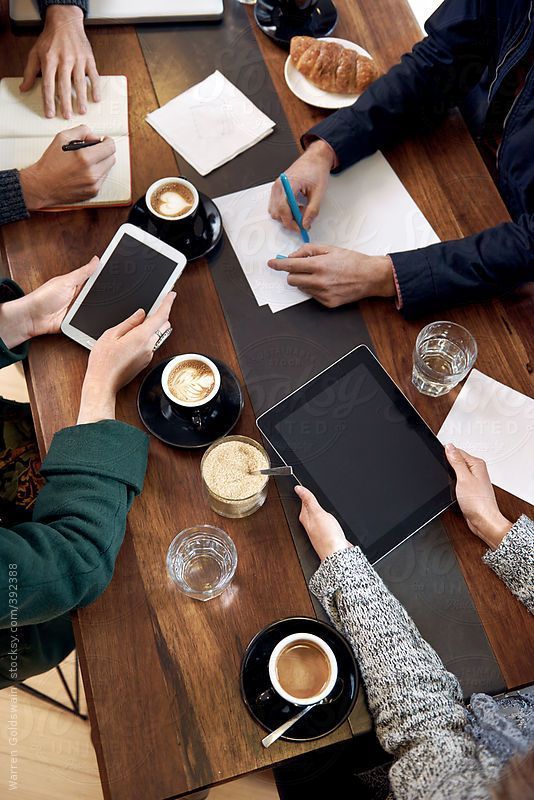 people sitting at a table with tablet computers and coffee