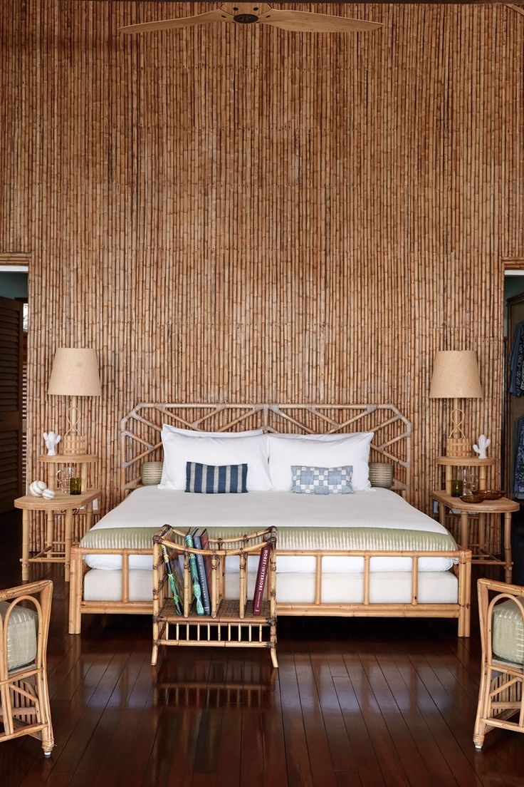 a bedroom with bamboo walls and flooring has a bed, two nightstands, and chairs