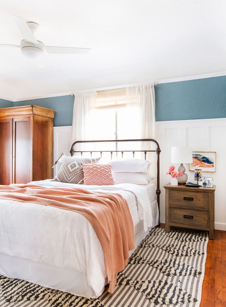 a bedroom with blue walls and white bedding has a striped rug on the floor