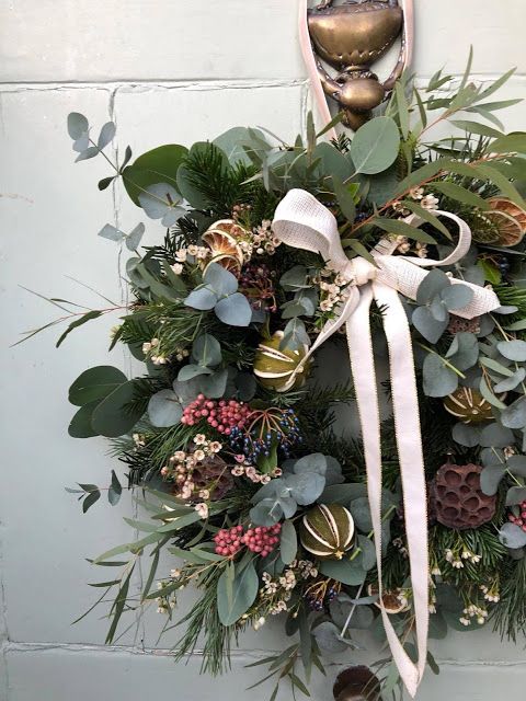 a wreath hanging on the side of a building with bells and greenery around it