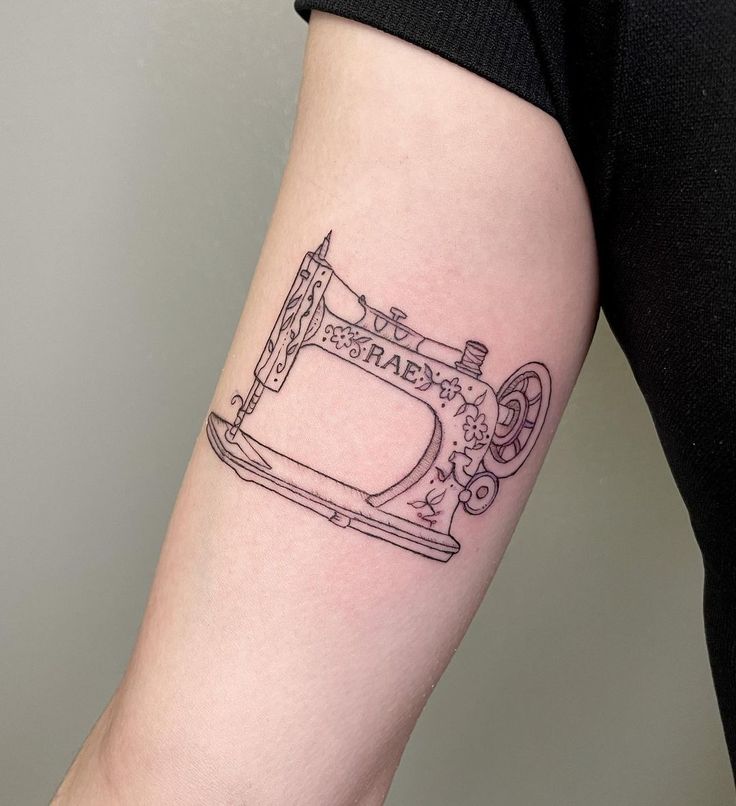 a woman's arm with a sewing machine tattoo on the left side of her arm