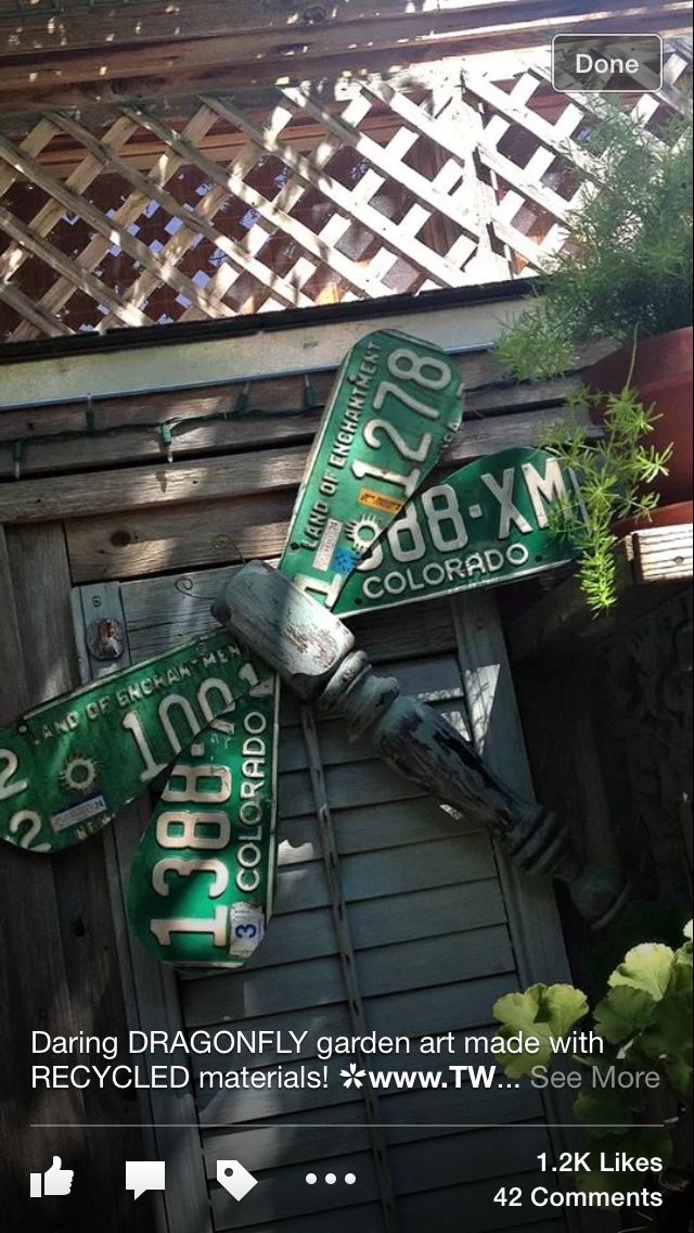 two green street signs mounted to the side of a wooden building with plants growing on top