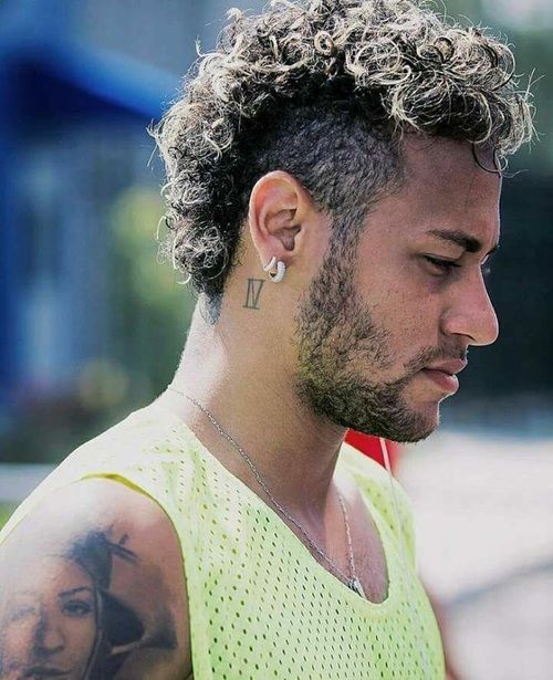 a close up of a person wearing a yellow shirt with tattoos on his arm and shoulder