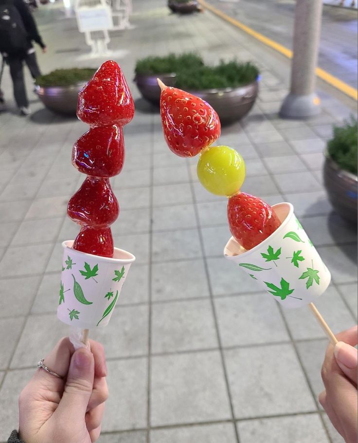 someone is holding up some fruit lollipops on a stick in their hand