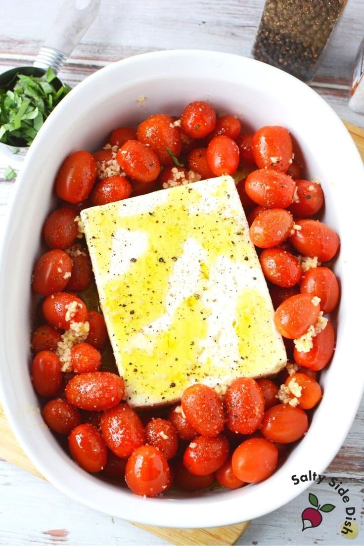 a white bowl filled with tomatoes and topped with a square piece of cheese on top